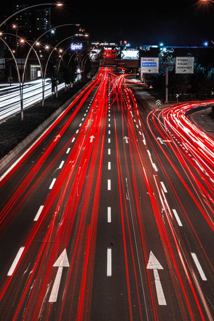 Long exposure capturing vivid red light trails on a busy highway at night.