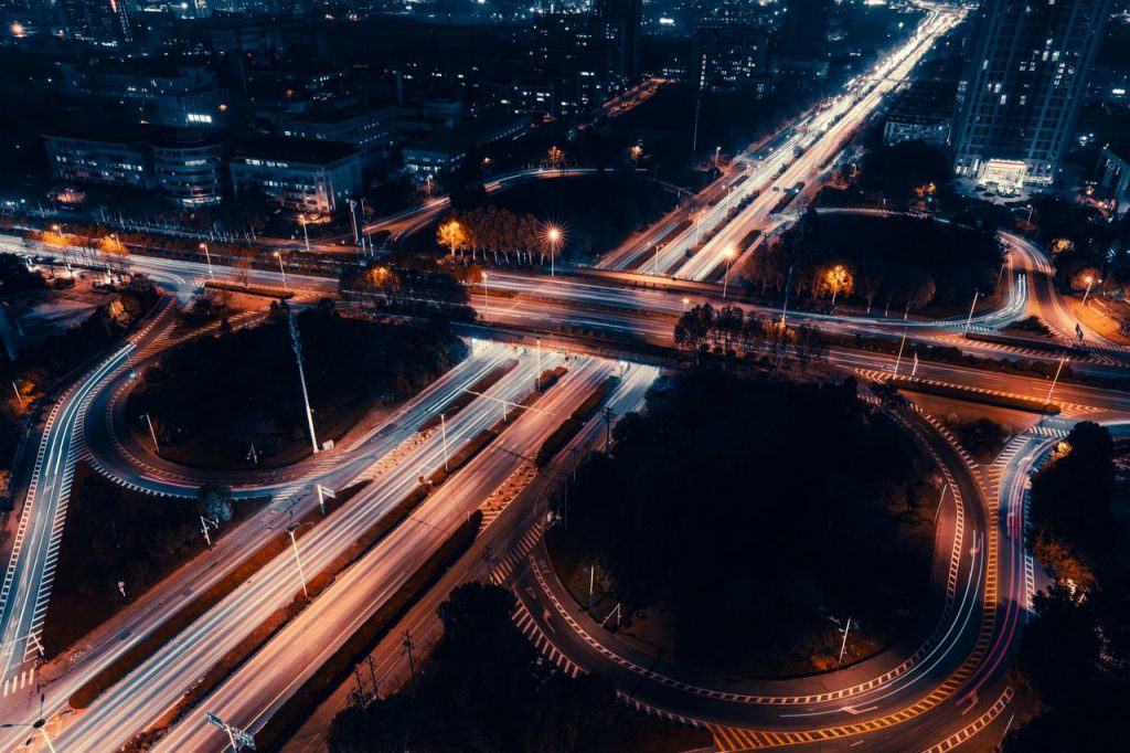 A vibrant aerial shot of city roads with light trails at night, showcasing urban energy.