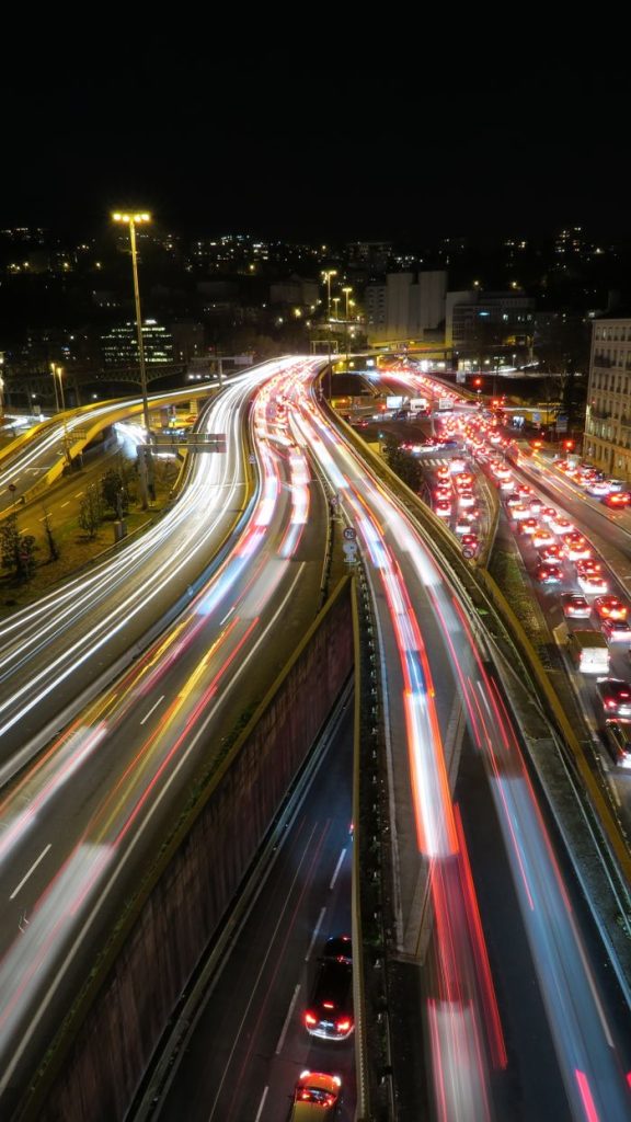 Long exposure of city highway showing vibrant light trails and bustling urban traffic at night.